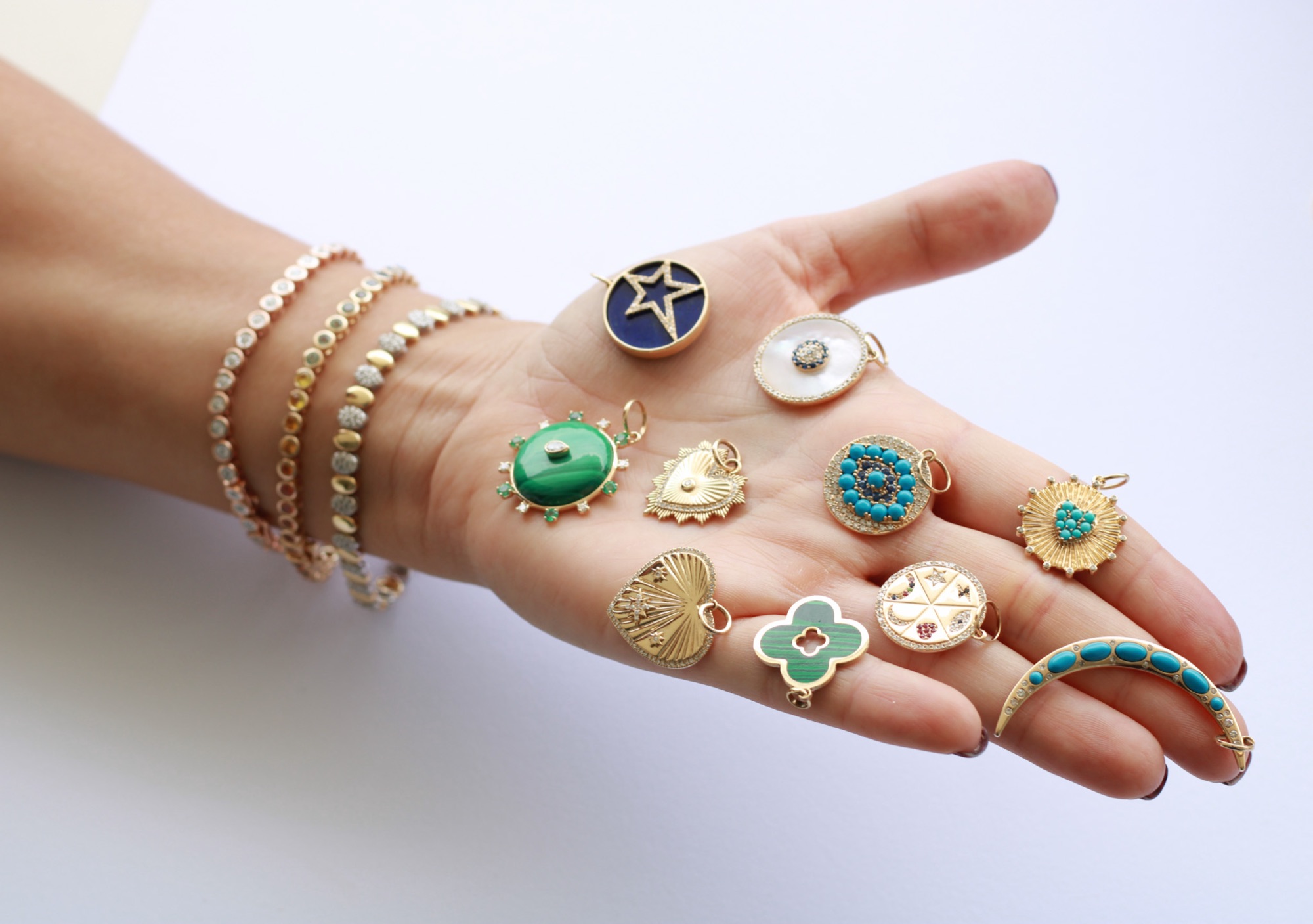 Hand with gold charms and diamond bracelets, Mishira